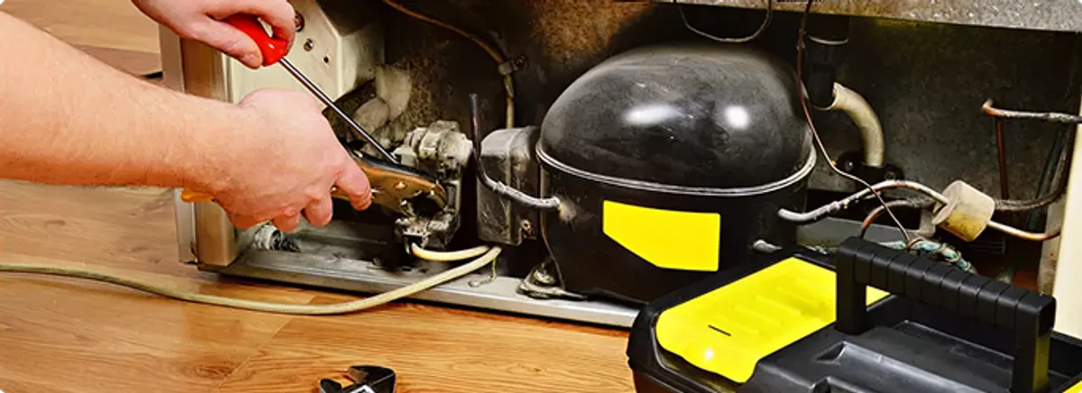 Refrigerator repair technician fixing the compressor and wiring in Austell, GA
