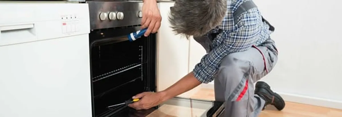 Oven repair technician inspecting and servicing an electric oven in Marietta, GA