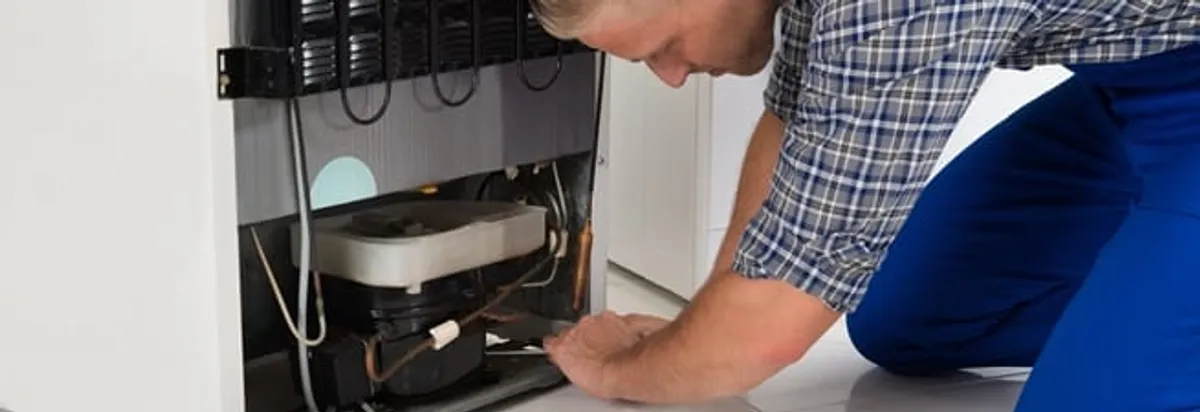Refrigerator repair technician servicing the compressor and condenser area in Marietta, GA