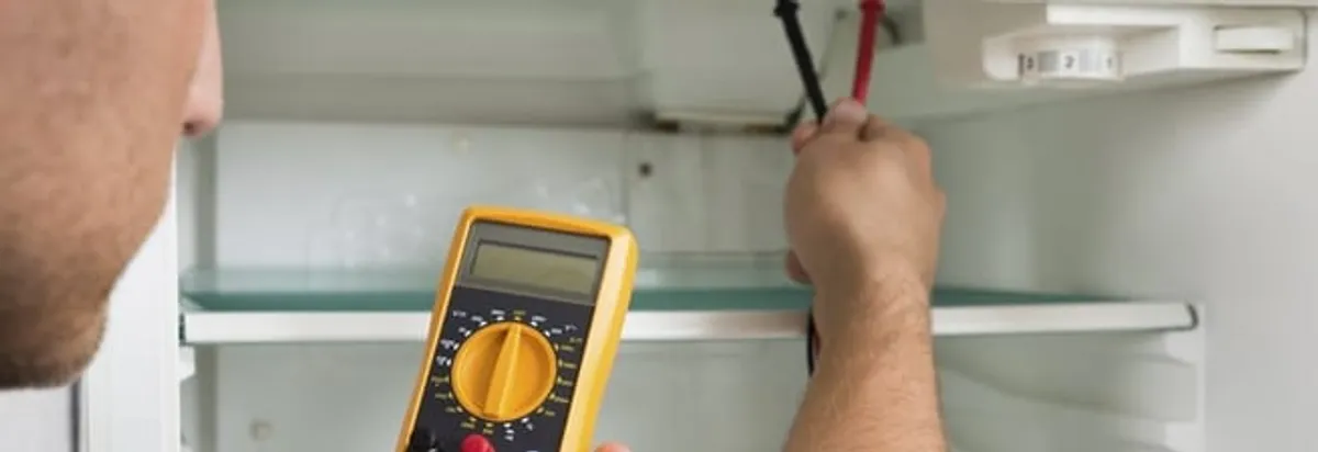 Refrigerator repair technician testing electrical components with a multimeter in Marietta, GA