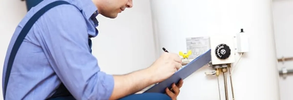 Water heater repair technician inspecting the unit and recording service notes in Marietta, GA